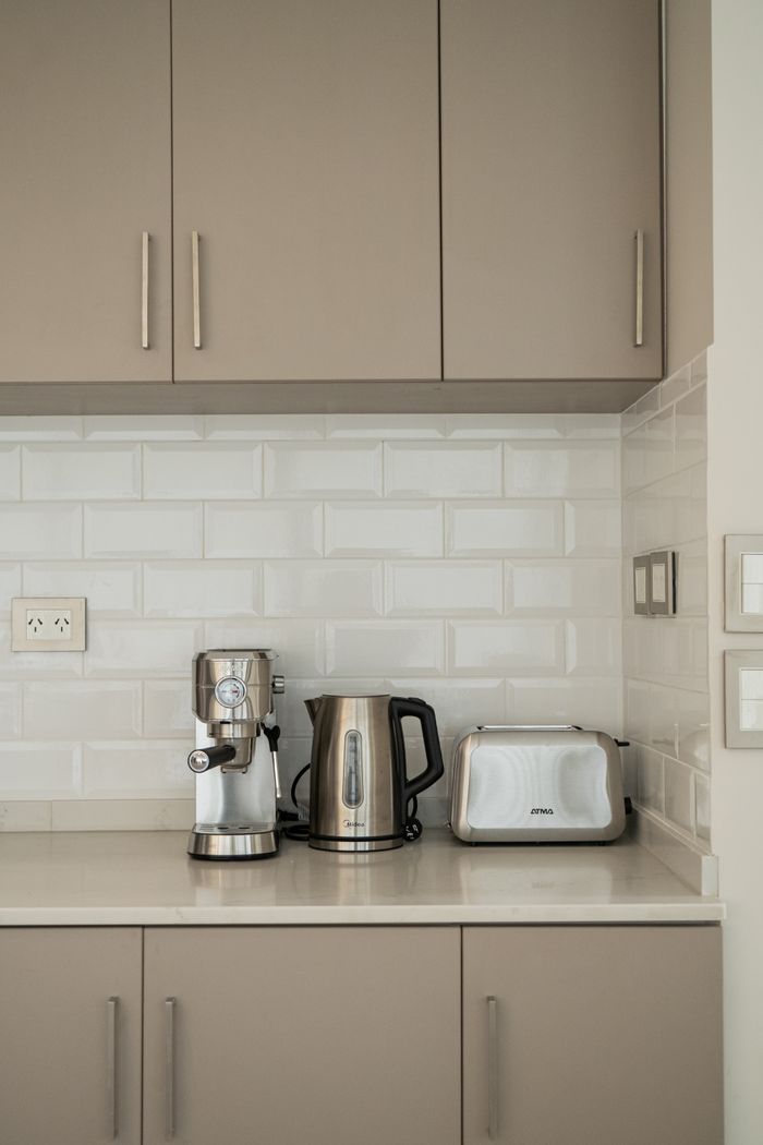 Elegant modern kitchen with appliances like a coffee maker, kettle, and toaster on a clean counter.